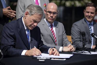 Gov. Greg Abbott signs Senate Bill 2 to limit property tax growth during a press conferance at Wally's Burgers in Austin on June 12, 2019.